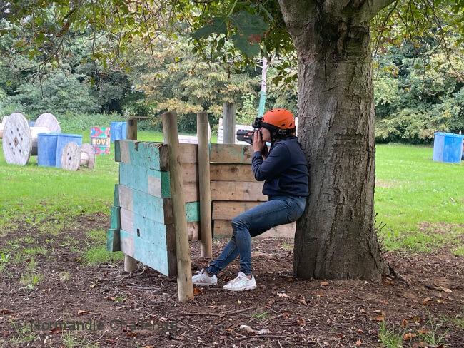 joueur caché derrière un arbre au laser game outdoor